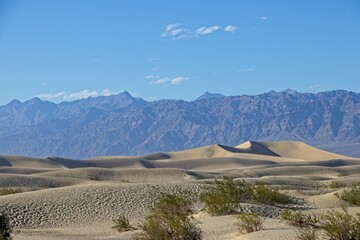 Fototapeta na wymiar The Mesquite Flat sand dunes rise above Stovepipe Wells in Death Valley, with the Panamint Range and Grapevine Mountains rising aove the valley on both sides.