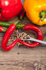 Colored peppers and spices on wooden background. Healthy food