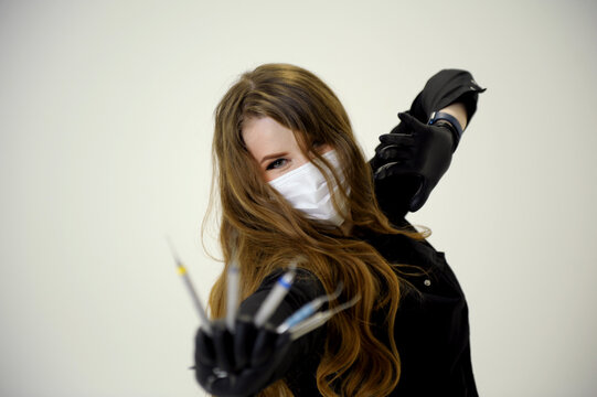 Beautiful woman dentist in black suit with a white mask with flowing hair holds in her hands scaler and curette Hand stretched forward selective focus bright photo of gorgeous woman