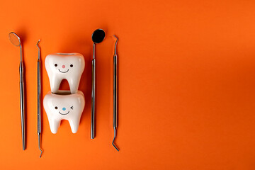 on an orange background, figures of teeth and dentist's tools. Teeth whitening and dental health in...