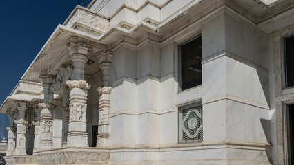 Beautiful white marble Lakshmi Narayan Temple (Birla Mandir). The columns are decorated with carved relief figures and ornaments. Blue sky. India. Jaipur