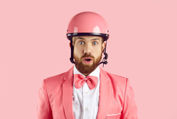 Headshot of young man with ginger beard, wearing modern pink bike helmet, stylish funky suit and...