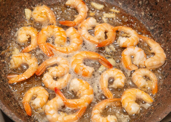 Shrimps are fried in oil in a frying pan