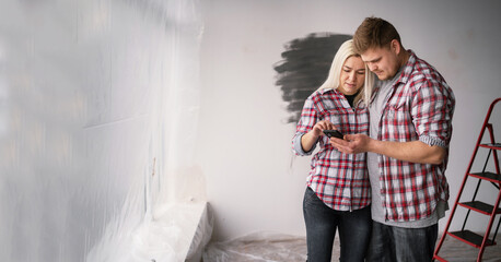 Young man showing design project on smartphone to focused woman indoors. Happy couple making...