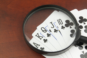 Game and gambling rules review concept. Playing cards under magnifying glass.