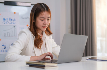 Focused female manager typing on laptop keyboard, checking email, taking part in online meeting at office desk.