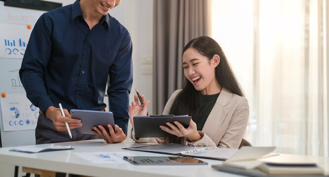 Image of happy young business people laughing while collaborating on a new project in creative office.