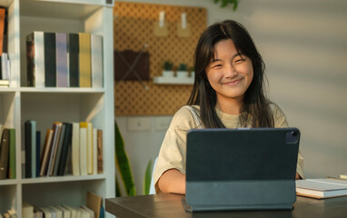 Portrait of smiling asian  girl using laptop, browsing internet, studying online at home.  Distance education and technology.