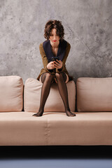 Obraz premium Young woman is going on date and calls taxi sitting at home on couch