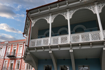 An old wooden balcony with columns on the facade of a building.