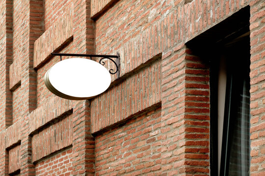 Close-up Outdoor Oval Advertising Sign On A Brick Wall.