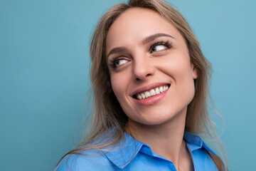 photo of shy cute casual young woman with smiling eyes on bright blue background