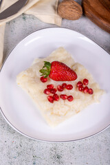 Gullac dessert. Traditional Ramadan dessert. Gullac dessert with pomegranate and strawberry on the plate. Close up