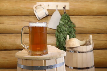 In the bath house, on an upside-down wooden barrel, there is a glass mug of light beer against the...