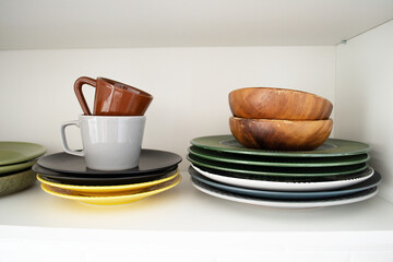 Dishes on a shelf in a white kitchen cabinet.