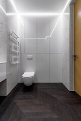 A luxurious interior in the bathroom with a bathroom, a shower on a shelf and a walk in the shower. White marble and dark brown floor. White cranes and plumbing