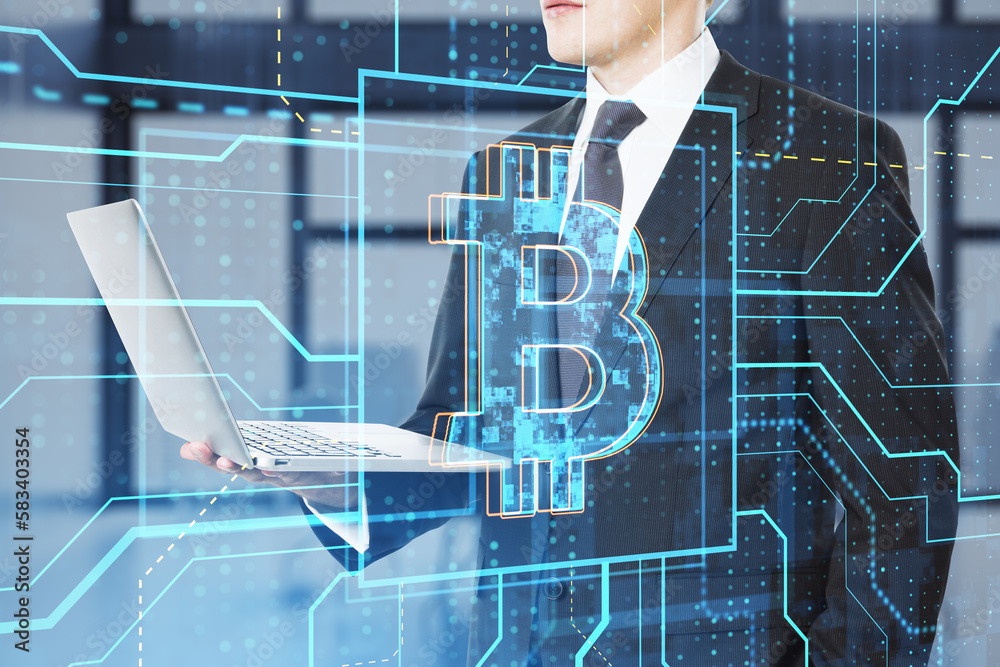 Poster close up of businessman hand using laptop with glowing linear bitcoin hologram on blurry office inte