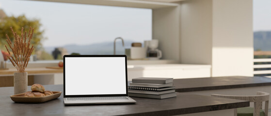 Laptop mockup on modern black kitchen countertop over blurred modern kitchen background