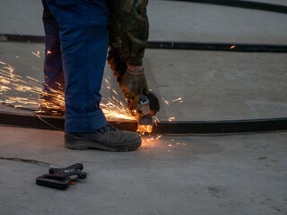 Worker cutting metal with angle grinder at construction site, closeup