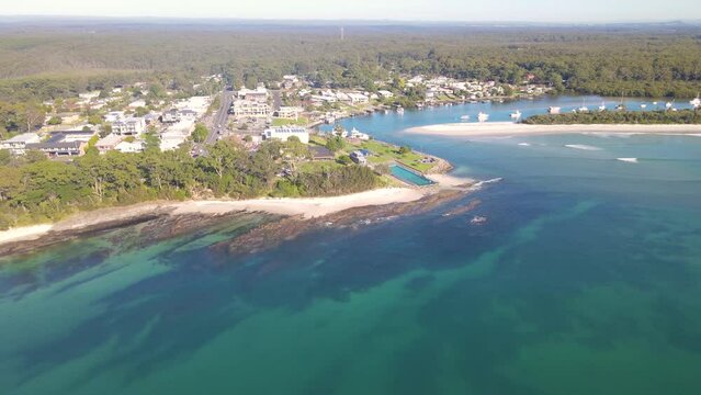 Aerial drone view of Huskisson in the City of Shoalhaven on the shores of Jervis Bay, NSW, Australia, showing Huskisson Sea Pool, Voyager Park and Currambene Creek on a bright sunny morning    