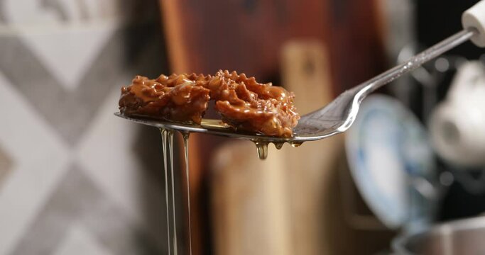 Experience the golden chebakia pieces delicately immersed in sweet honey, creating a luscious coating that enhances their flavor and texture