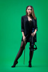 Violinist woman in the black blazer on the green background.
