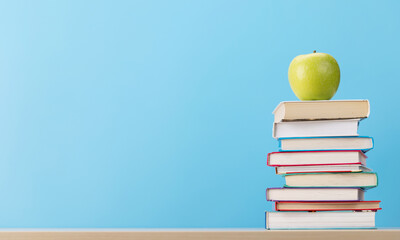 Stack of books on desk and apple