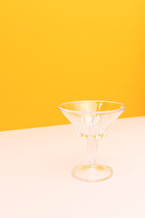 Small crystal glass in front of yellow background. Place for your design.