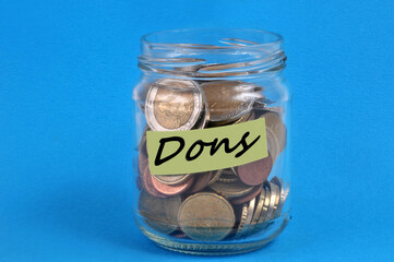 Pot en verre rempli d'argent avec une étiquette sur laquelle est écrit dons sur fond bleu