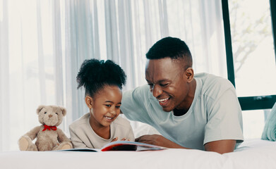 Father reading a daytime story with his daughter at home