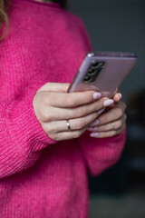 Mobile phone in female hands. A wedding ring on the finger