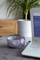 A beautiful cup filled with coffee and a laptop. Work at home