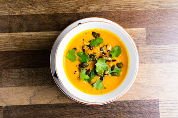 Pumpkin cream soup with parsley on gray stone and wooden background. Top view, copy space
