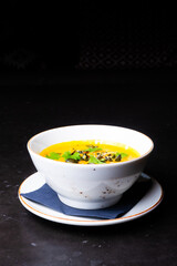 Pumpkin cream soup with parsley on gray stone and wooden background. Top view, copy space