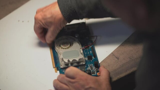 a man with a screwdriver collects a video card fan. clean video card contacts. close-up of a video card heatsink. High-quality shooting in 4k format