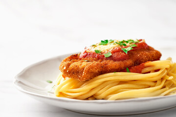 Chicken Parmesan and spaghetti in a plate with copy space. Low angle view.