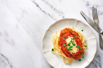 A plate of Chicken Parmesan and spaghetti with copy space. Top view.