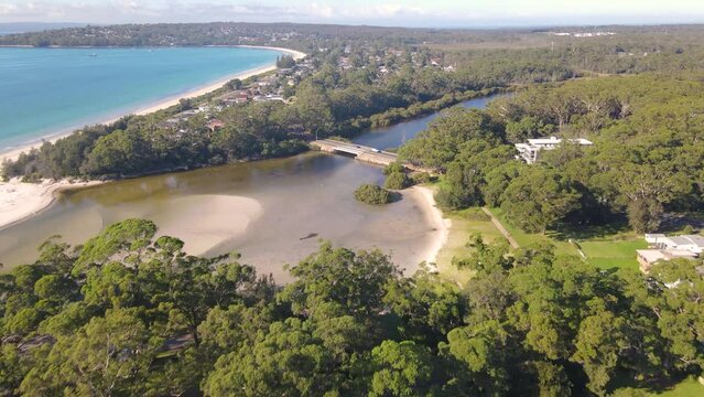 Aerial drone view of Huskisson in the City of Shoalhaven on the shores of Jervis Bay, NSW, Australia, heading toward Moona Moona Creek on a bright sunny morning    