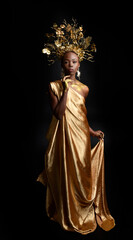  fantasy portrait of beautiful african woman model with afro, goddess silk robes and ornate floral wreath crown. gestural Posing holding golden flowers. isolated on dark  studio background 
