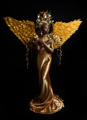  fantasy portrait of beautiful african woman model with afro, goddess silk robes, ornate crown & gold angel wings.  gestural Posing holding golden flowers., isolated on dark  studio background 