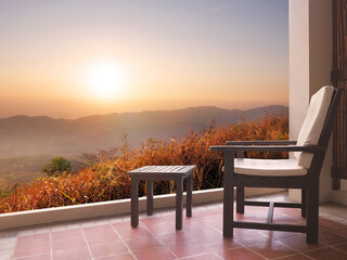 Vintage chair and coffee table on balcony in front of resort over sunset mountain view