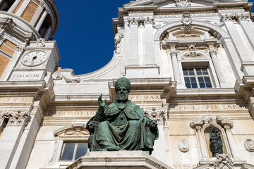 Fototapeta na wymiar LORETO, ITALY, JULY 5, 2022 - Pope Sixtus V's Monument with the facade of Shrine of the Holy House of Loreto with in Loreto, Italy