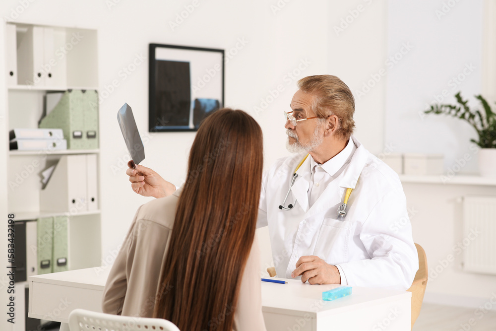 Wall mural Orthopedist showing X-ray picture to patient in clinic