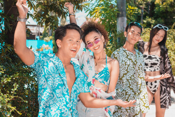Four happy asian friends posing in colorful summer wear at a resort. Two couples on a double date...
