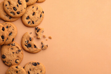 Many delicious chocolate chip cookies on beige background, flat lay. Space for text