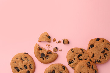 Many delicious chocolate chip cookies on pale pink background, flat lay. Space for text