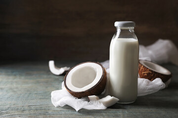 Bottle of coconut milk and nuts on wooden table, space for text