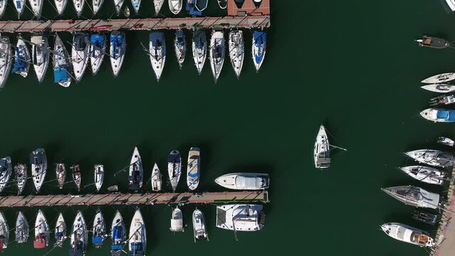 Aerial view of a Small sail boat leaving a marina slowly 