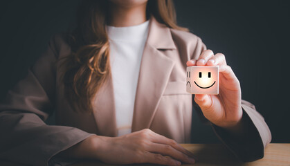 Businesswoman choosing on the happy Smile face icon give satisfaction in good service, Smile face and sad face on wooden block cube for positive mindset selection. Mental health and emotional state