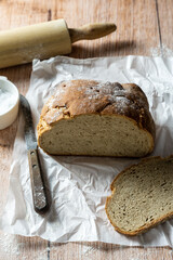 Gebackenes Brot, ein Messer und Salz auf einem rustikalen Holztisch. Brotzeit. 